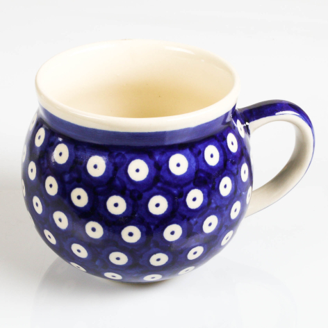 Deep blue ceramic pitcher with white dot pattern and cream-colored interior, rounded bulbous shape with curved handle
