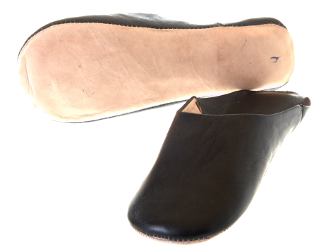 Black leather shoe with natural suede sole, angled side view showing curved profile and crafted details