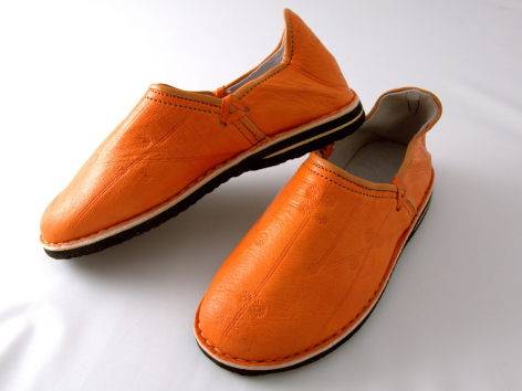 Pair of burnt orange leather slip-on shoes with brown sole, angled front view showing rounded toe shape