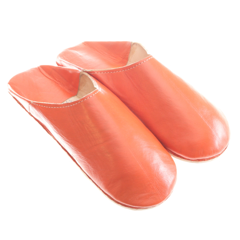 Pair of coral leather slippers with soft rounded toe and cream interior lining, front three-quarter view