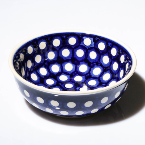 Deep blue ceramic bowl with white polka dot pattern, angled three-quarter view showing interior and curved sides
