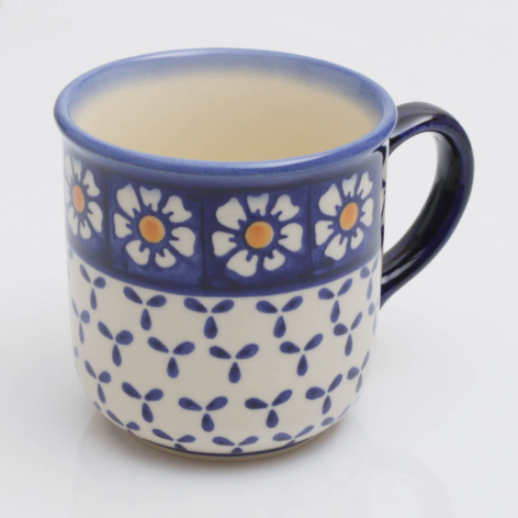 Blue ceramic mug with white polka dot base and decorative daisy flower band, front view