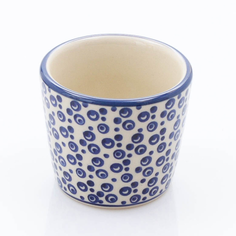 Cream ceramic cup with blue leopard spot pattern and rim, cylindrical shape, front view