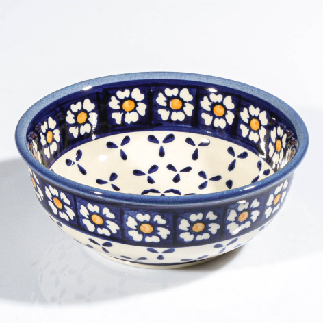 Deep blue ceramic bowl with cream interior, scattered white flowers and blue dots, overhead view