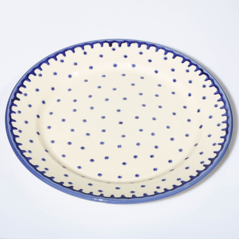 Cream ceramic plate with blue dotted rim and scattered blue dot pattern, top view
