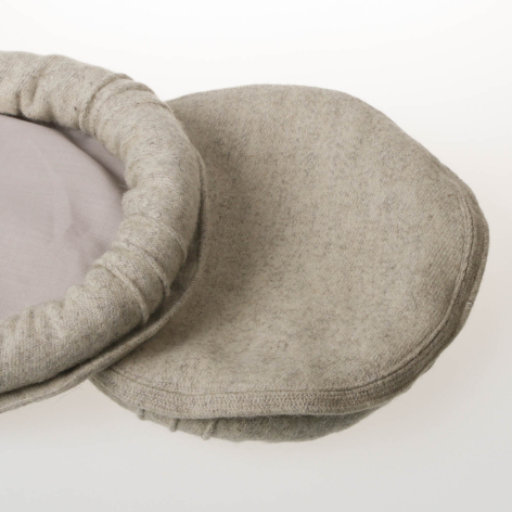 Beige linen eye pillow with curved organic shape and soft padded edges, shown from above at an angle