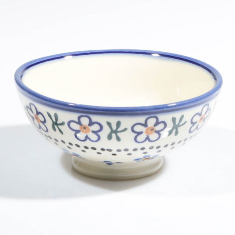Cream ceramic bowl with blue rim and hand-painted blue and red floral pattern around the exterior, front view