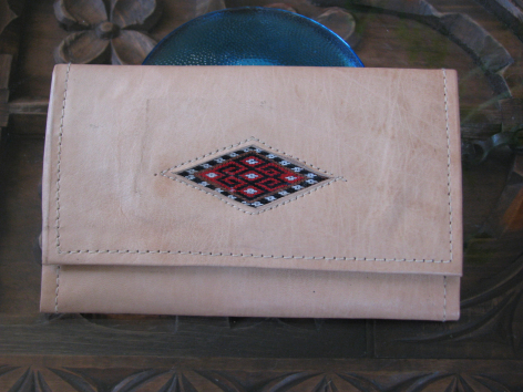 Cream linen wallet with burgundy and navy geometric embroidered diamond design on front flap, closed view