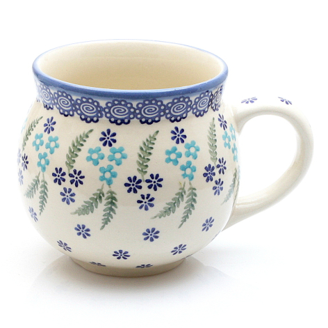 Cream ceramic mug with blue decorative rim and small floral pattern in blue and turquoise throughout body