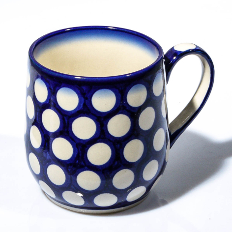 Navy ceramic mug with white polka dot pattern and cream interior, front view