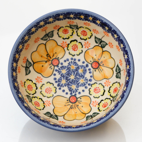 Ceramic bowl with blue rim, hand-painted orange citrus slices and blue florals on cream, overhead view