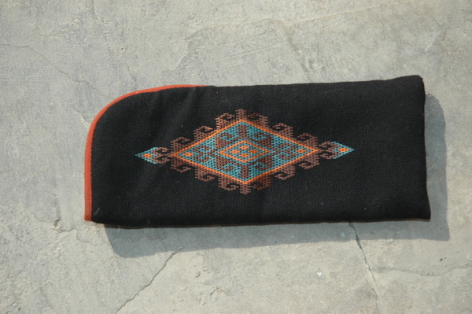 Portefeuille noir en textile avec broderie géométrique colorée au centre et bordure orange, vue de face