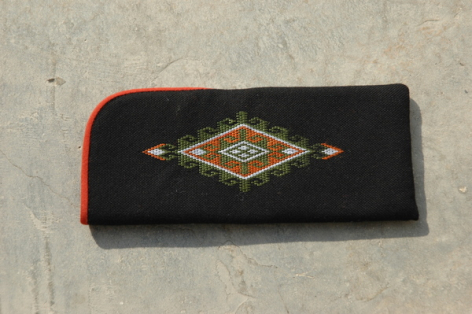 Portefeuille noir avec bordure orange et motif géométrique doré brodé au centre, vue de dessus