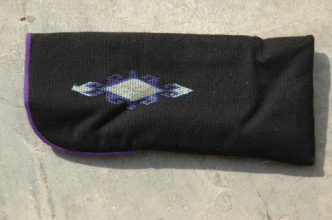 Black fabric pouch with blue and white diamond-shaped embroidered detail, front view