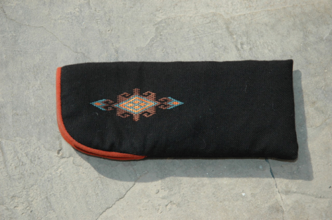 Black fabric clutch wallet with ornate gold embroidered central motif and red trim detail, front view on light surface