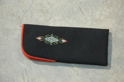 Black fabric wallet with red trim and embroidered geometric design, front view