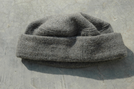 Coussin de cou gris en laine feutrée, vue de face montrant sa forme tubulaire enroulée