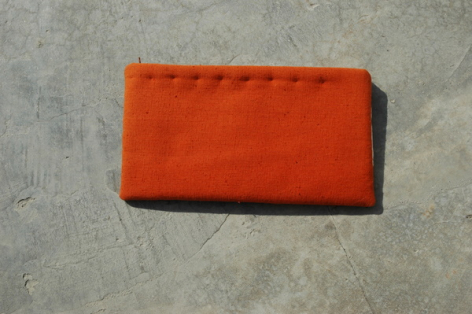 Portefeuille en cuir orange vif, vue de face, fermé avec piqûres visibles