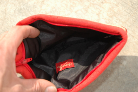 Petit pochette rouge vif en cuir avec intérieur noir, vue de face ouverte, tenue à la main