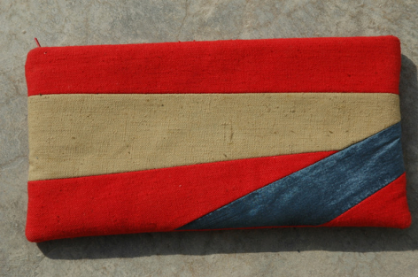 Red and natural linen textile with navy blue diagonal stripe, laid flat on neutral background