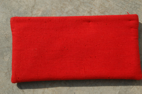 Red leather clutch with rounded corners, front view on neutral background