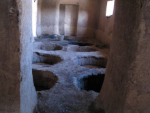 Intérieur d'une pièce en adobe aux murs beiges avec des ouvertures rectangulaires laissant passer la lumière naturelle