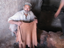 Artisan présentant un textile teint de couleur beige clair, drapé entre ses mains, dans un atelier traditionnel